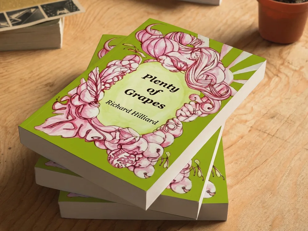 Plenty of Grapes by Richard Hilliard, a stack of copies on a wooden table, the cover a pink floral border around the title.