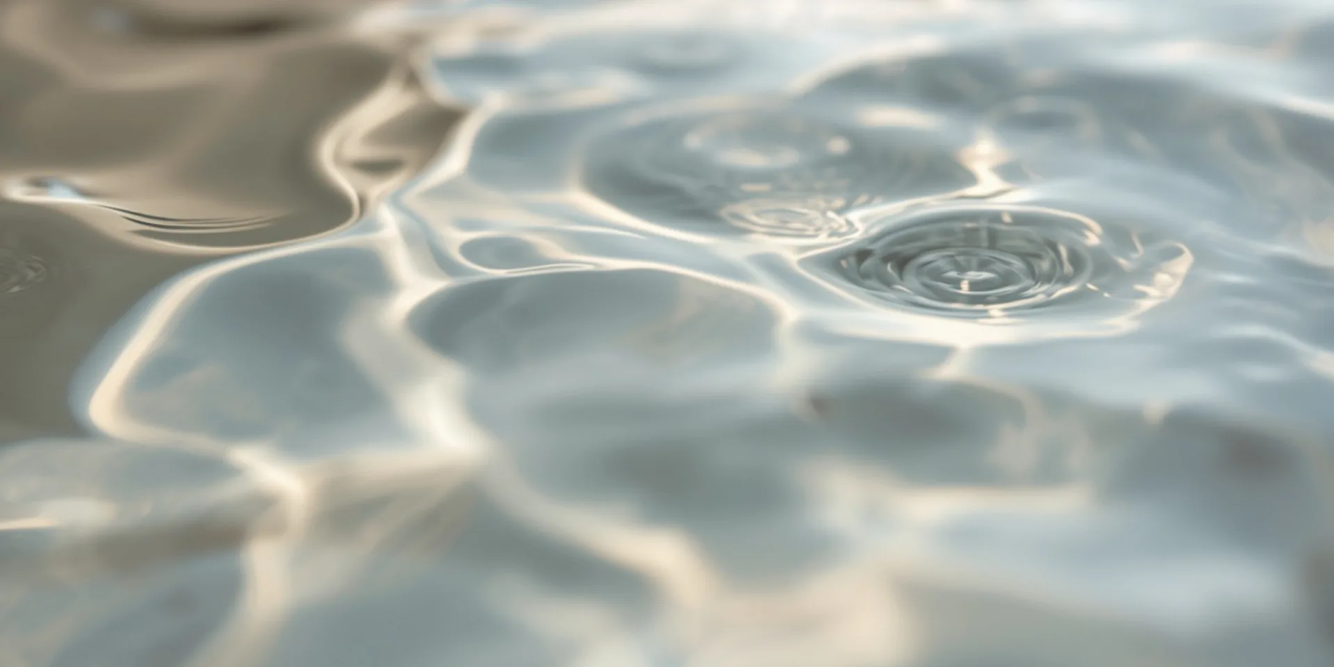 Calm water surface with gentle concentric ripples in soft light